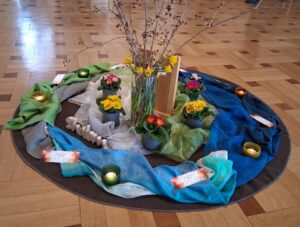 Ein Blumenstrauß zwischen Tüchern und Kerzen auf einem Parkettfußboden